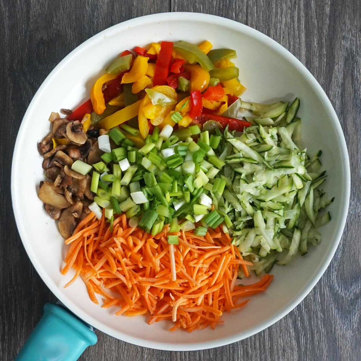 Skillet with fresh shredded veggies: zucchini, carrots, mushrooms, bell peppers and green onions