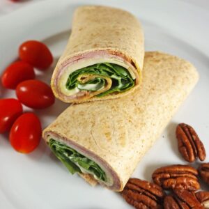 Low carb wrap with ham and cheese and a side of pecans and tomatoes