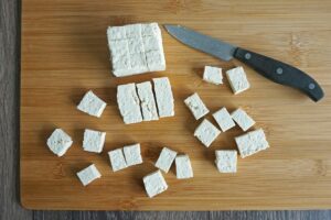 Cutting tofu into cubes on a cutting board