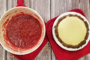 Bowl of raspberry jam next to the cooked cheesecake