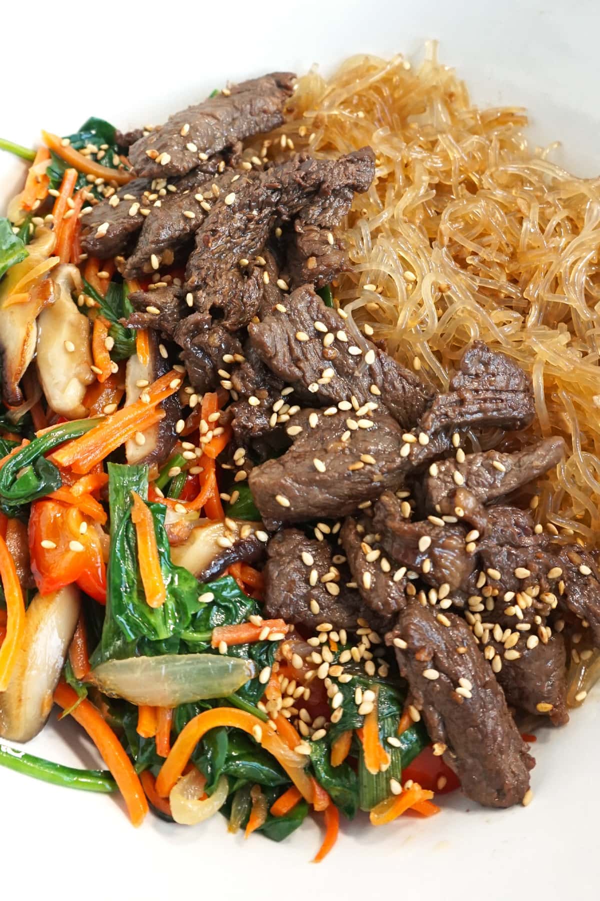 Bowl of cooked noodles, then beef, then veggies
