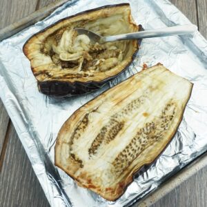 Roasted eggplant on a pan getting scooped with a spoon