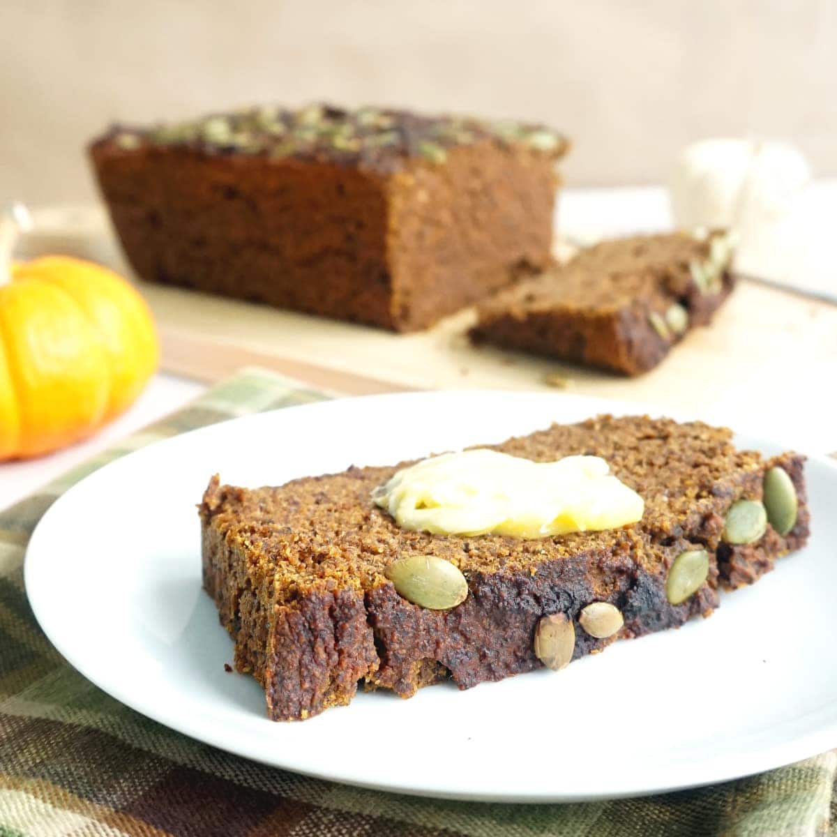 Slice of Hearty Keto Pumpkin Bread with Pecan & Flax, with butter on top