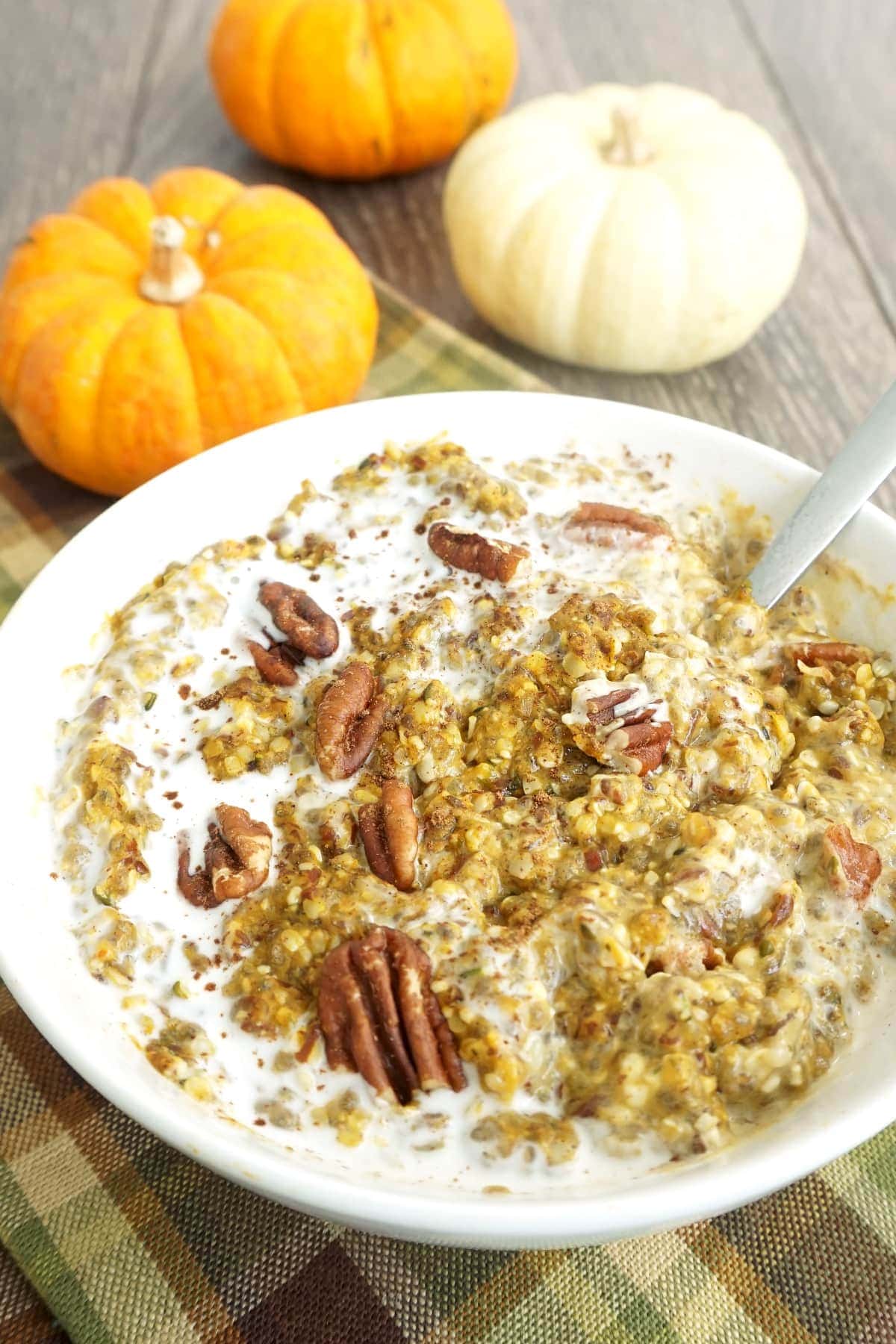 Bowl of keto low-carb pumpkin oatmeal with cream and pecans on top