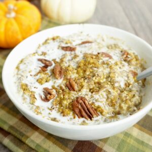 Bowl of keto low-carb pumpkin oatmeal with cream and pecans on top