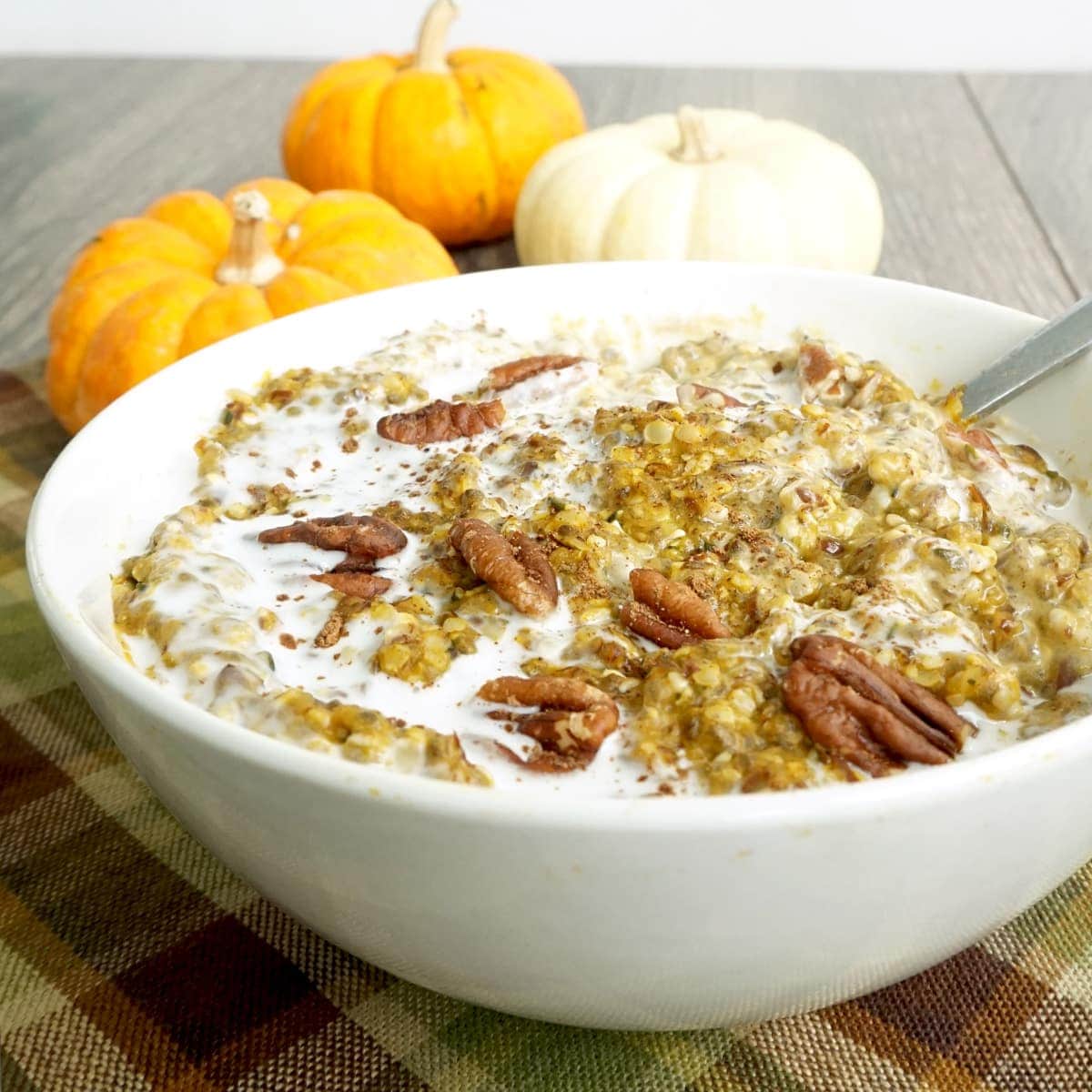 Bowl of keto low-carb pumpkin oatmeal with cream and pecans on top