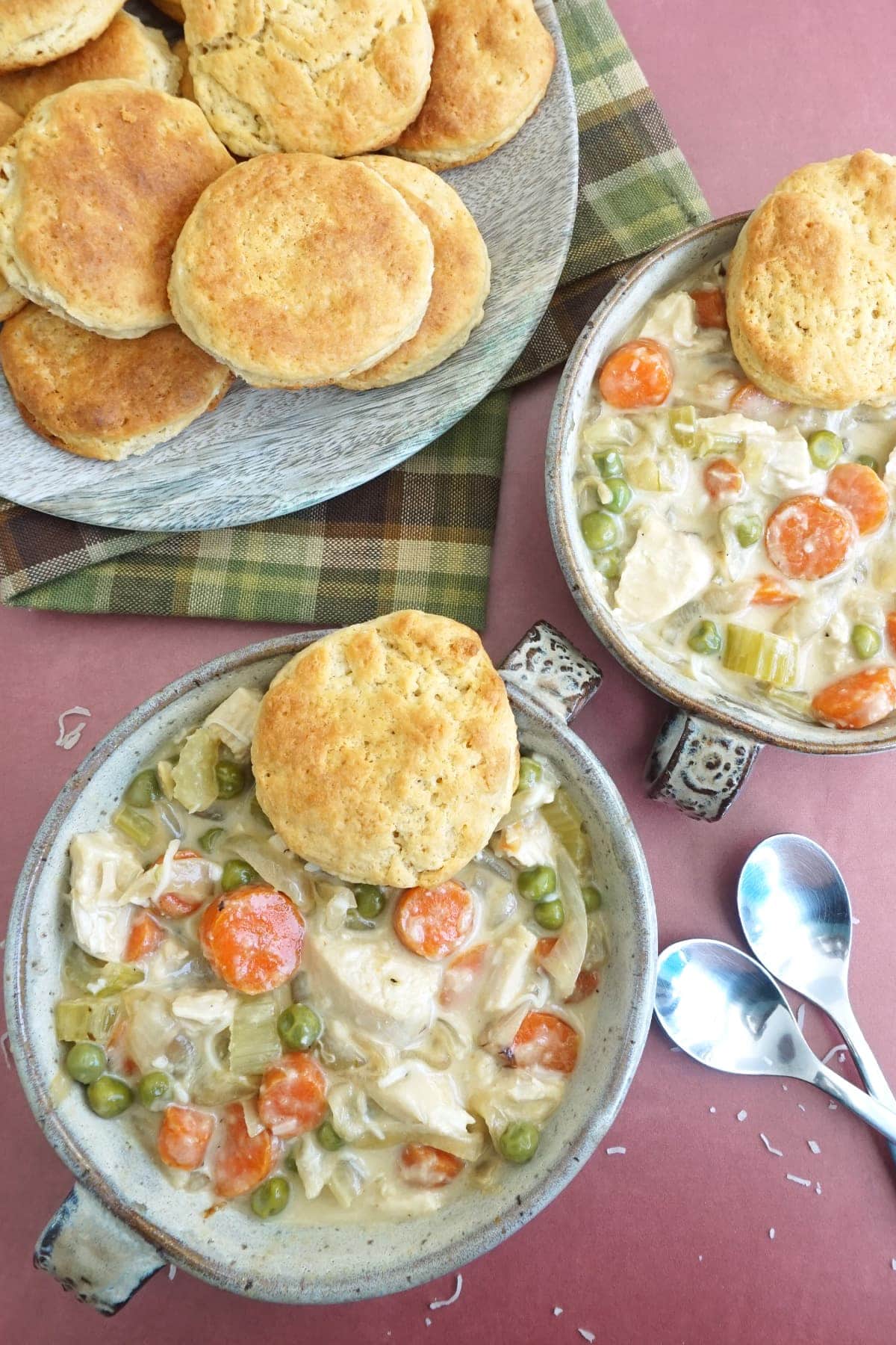 Two bowls of Crustless Chicken Pot Pie with a plate of biscuits on the side
