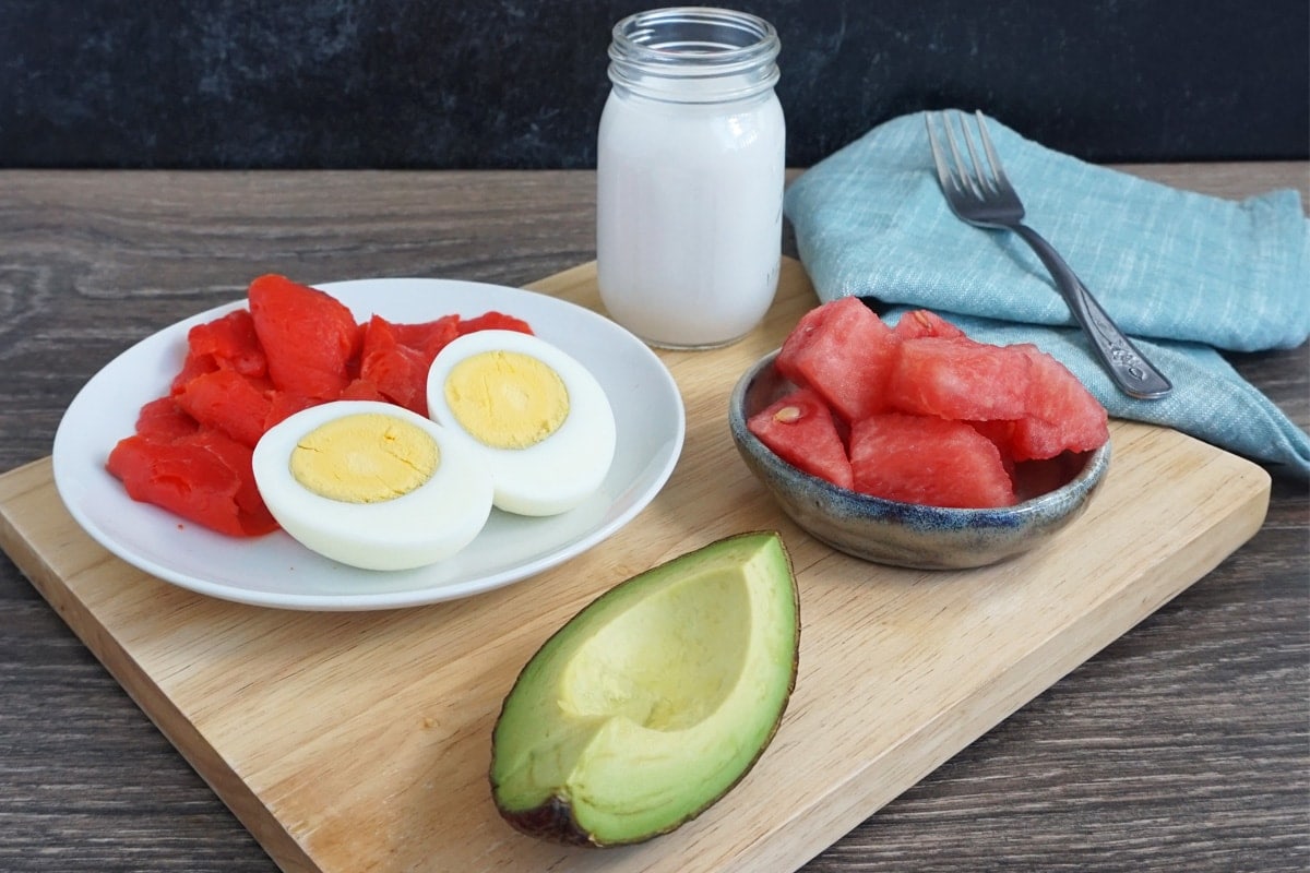 Breakfast Charcuterie Board: boiled egg, smoked salmon, watermelon, avocado and a glass of coconut milk