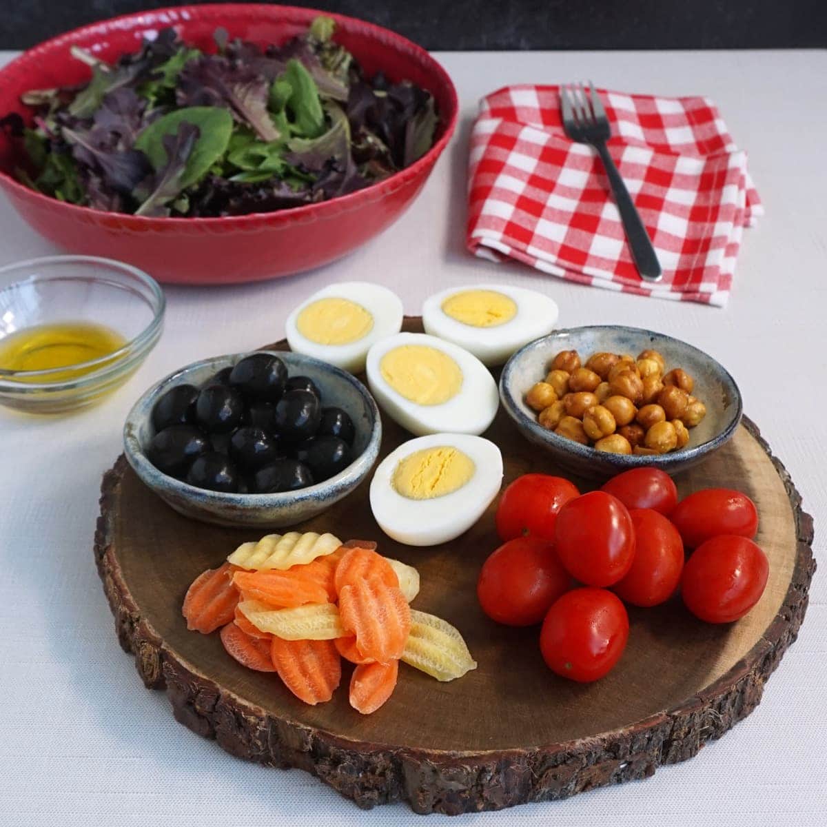 Charcuterie Board: cherry tomato, boiled eggs, carrots, olives, roasted chickpeas, with a side of greens and oil