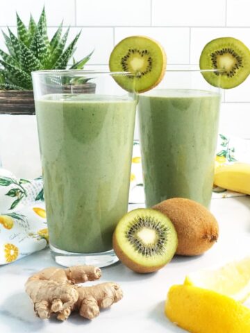 Two cups of Green Detox Smoothie with ginger, lemon, kiwi and a yellow straw