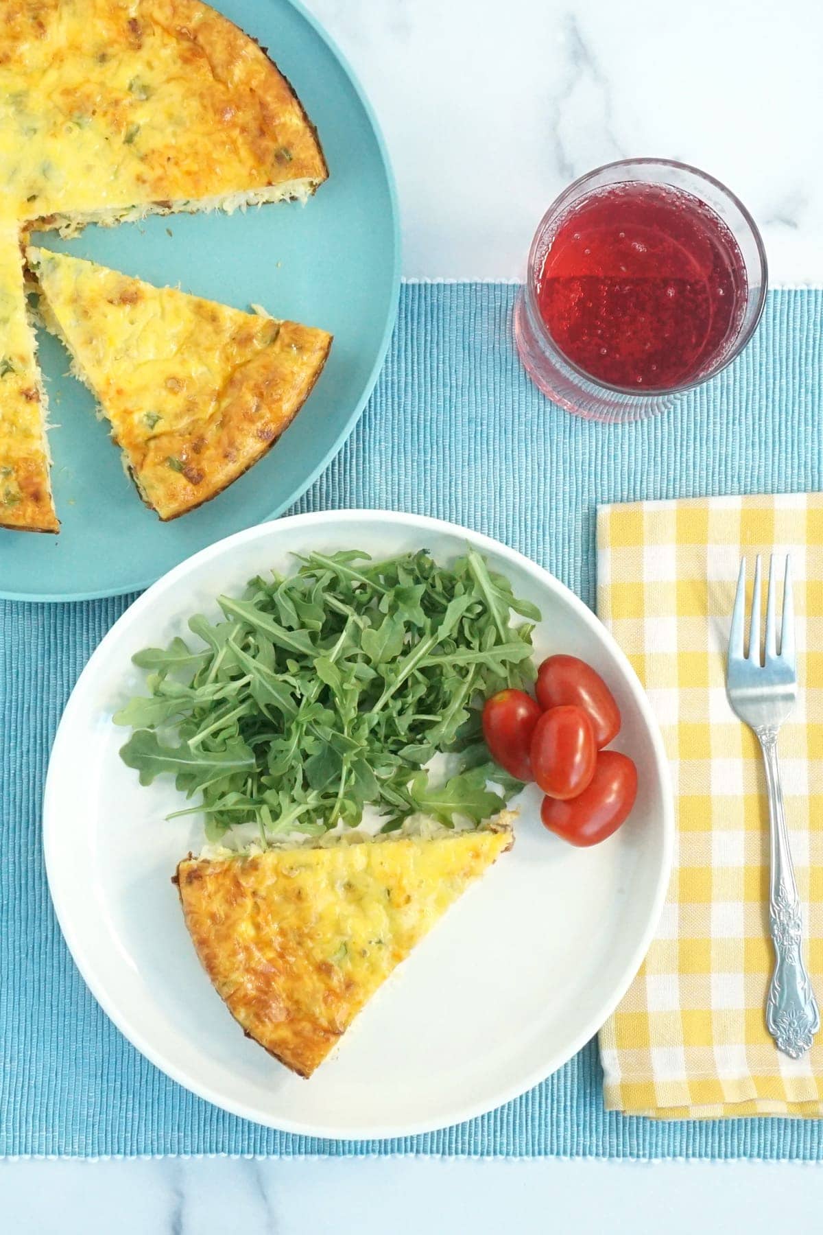 Plate of quiche with arugula and tomato on the side